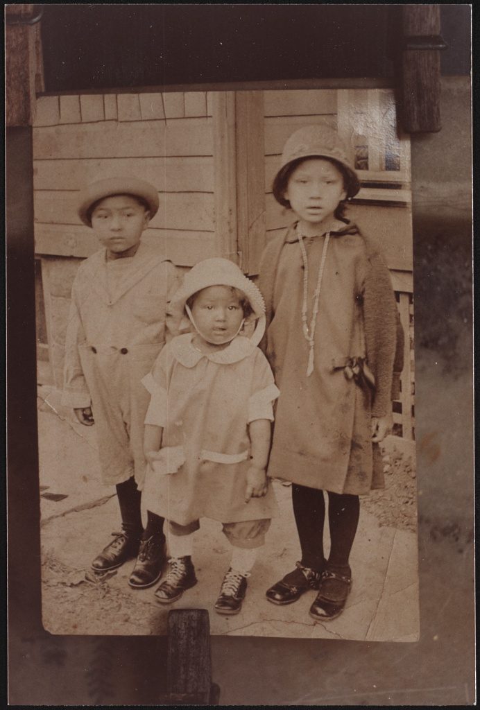 Three children standing on a wooden porch