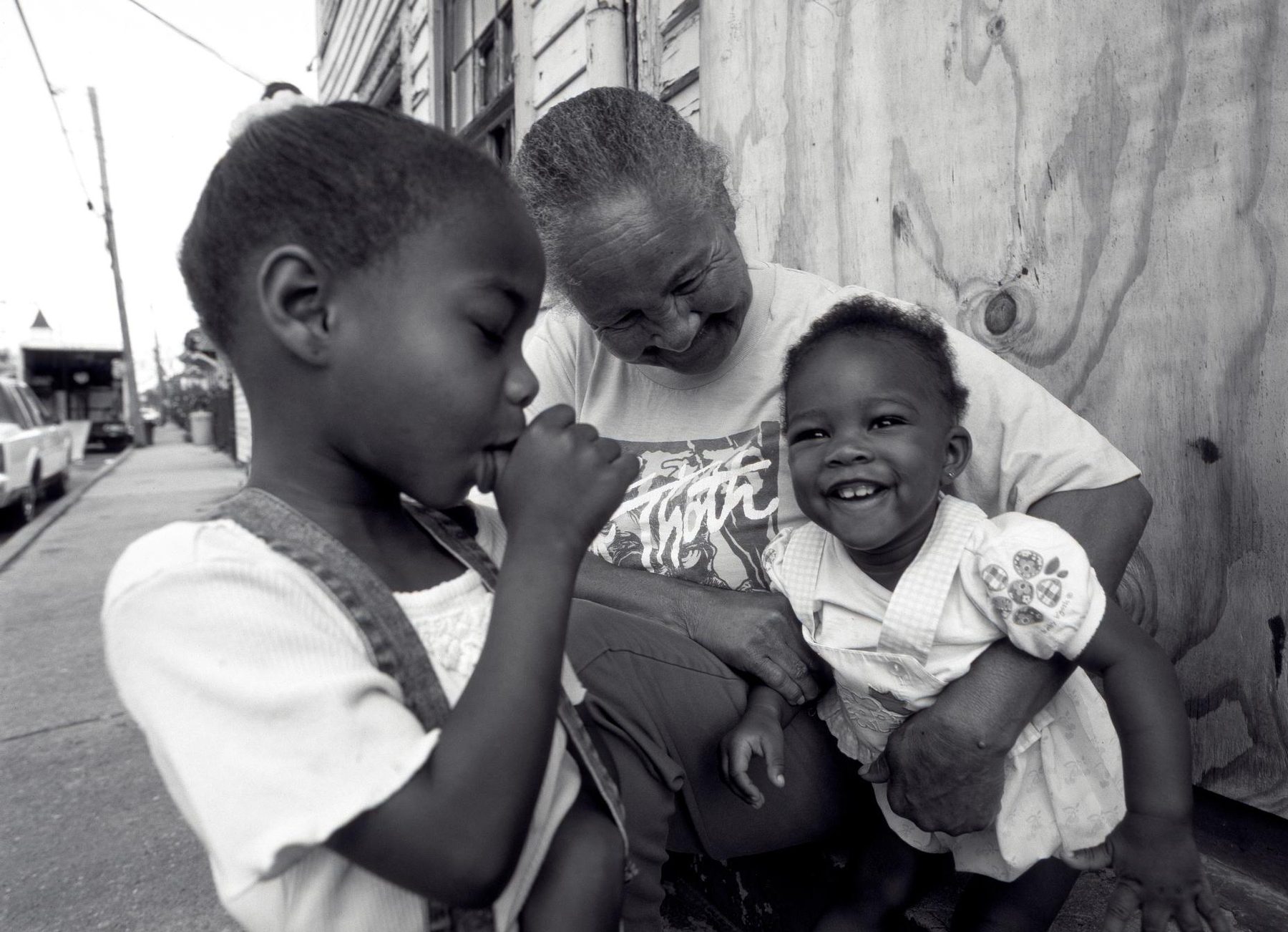 A grandmother laughing with a baby in her arms while an older child stands beside them